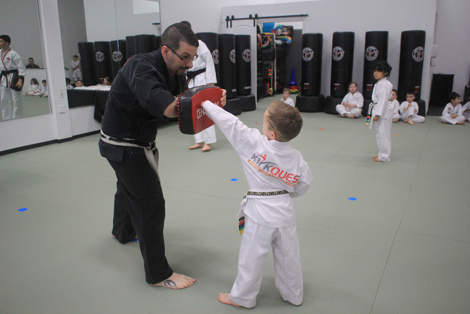 Instructor holding a pad as a young student strikes